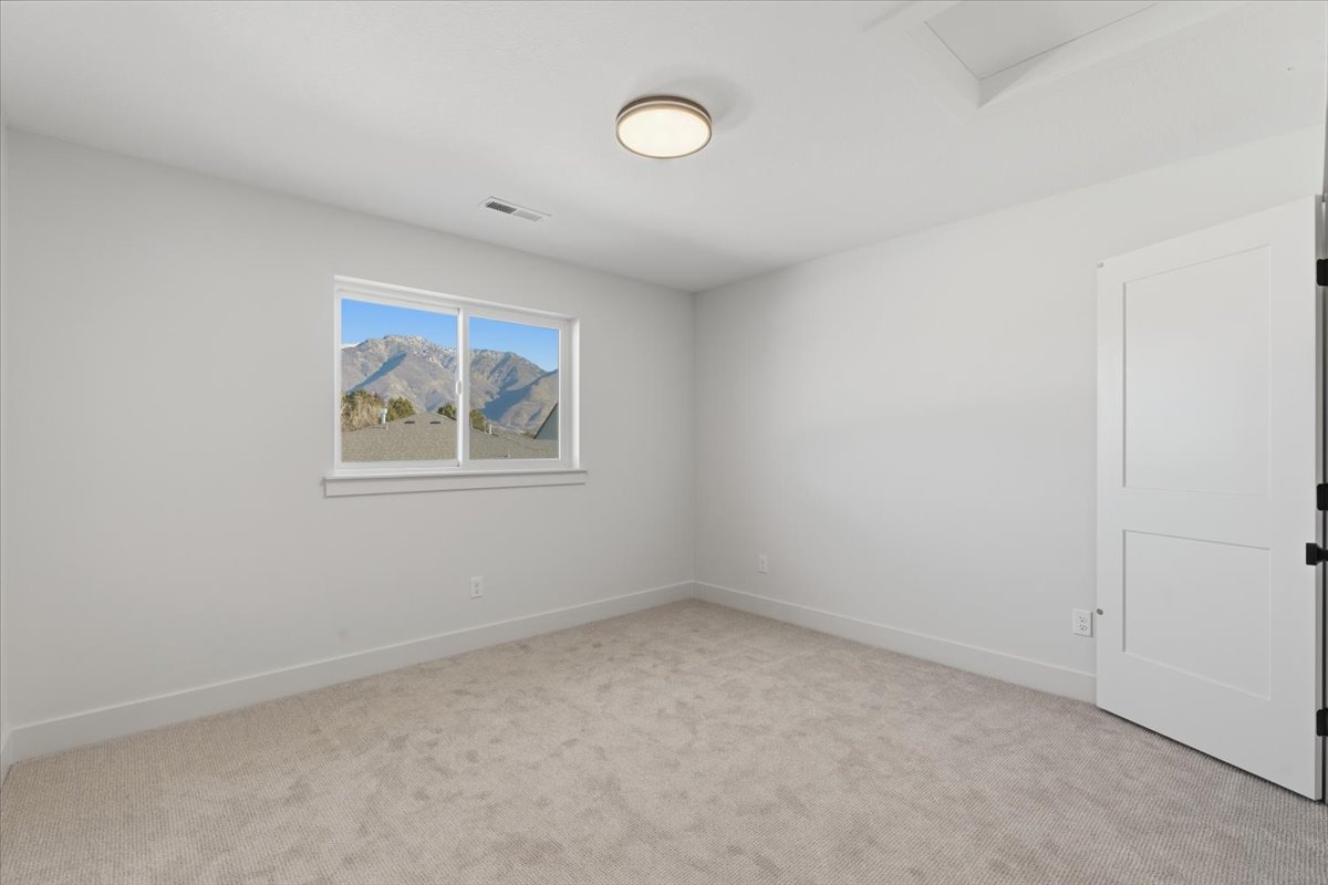Empty room featuring attic access and light carpet