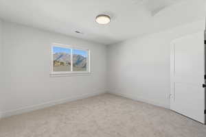 Empty room featuring attic access and light carpet