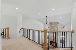 Hallway with vaulted ceiling, recessed lighting, an upstairs landing, and carpet