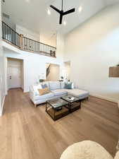 Living area featuring ceiling fan, light wood finished floors, a high ceiling, and recessed lighting