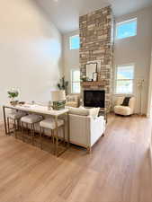Living area featuring a high ceiling, a stone fireplace, and light wood-type flooring