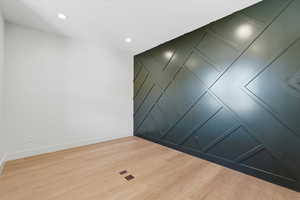 Empty room featuring a decorative wall, an accent wall, light wood-style floors, and recessed lighting
