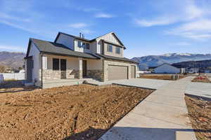 Craftsman house with a mountain view, a porch, a garage, stone siding, and concrete driveway