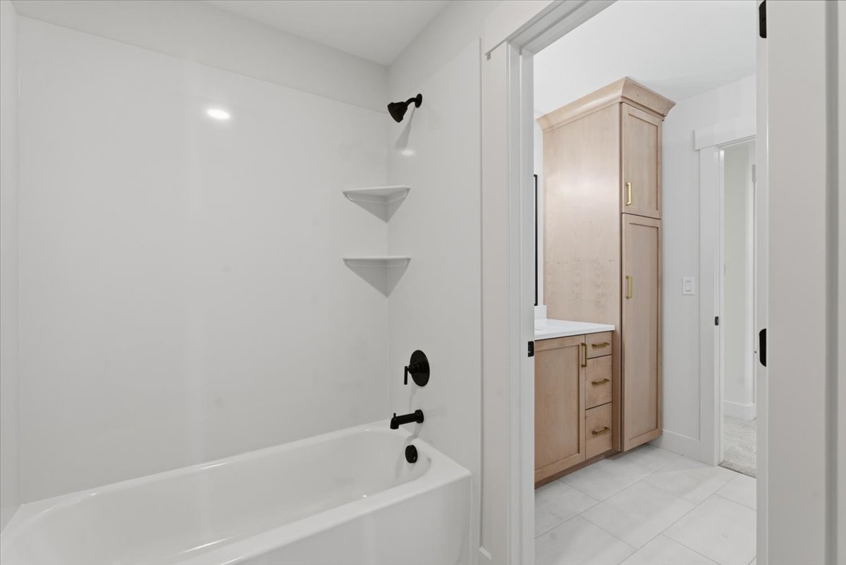 Full bathroom featuring tub / shower combination, vanity, and light tile patterned floors
