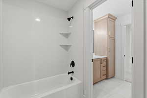 Full bathroom featuring tub / shower combination, vanity, and light tile patterned floors