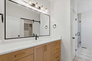 Full bath with light floors, vanity, and a stall shower