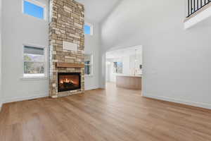 Unfurnished living room with light wood-style flooring, a high ceiling, and a fireplace