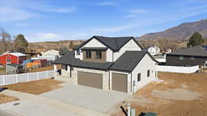 View of front of property with a shingled roof, concrete driveway, stone siding, a mountain view, and a garage