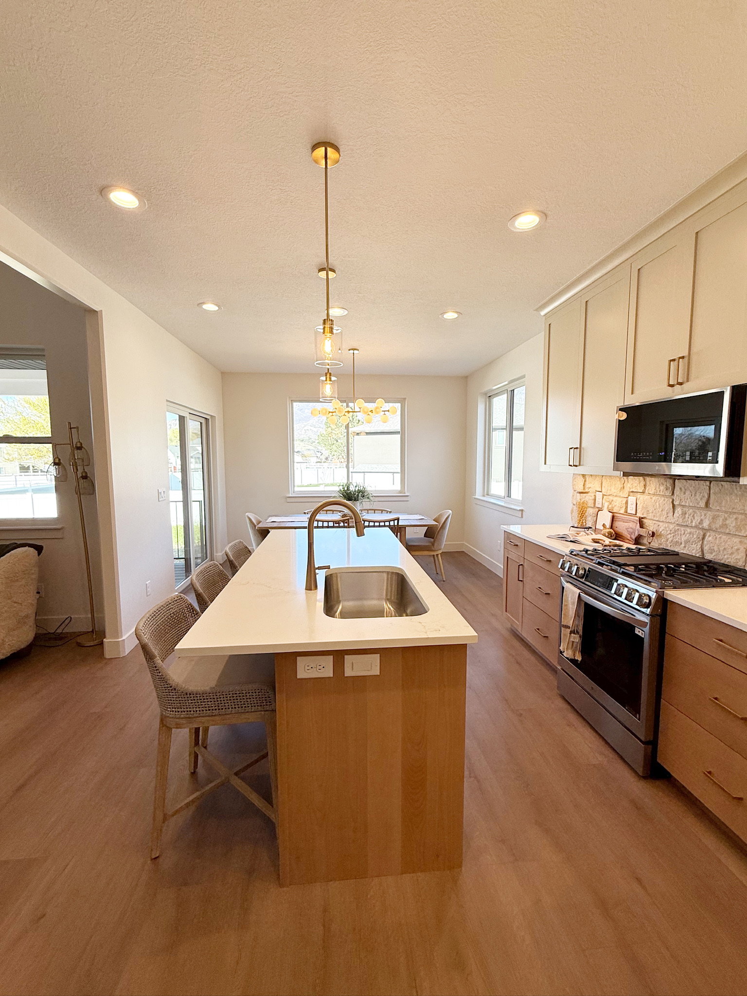 Dual tone kitchen with stainless steel appliances, pendant lighting, backsplash, a breakfast bar area, and light wood-type flooring
