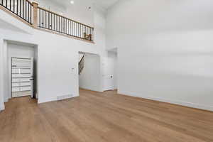 Unfurnished living room featuring a towering ceiling and light wood-style flooring