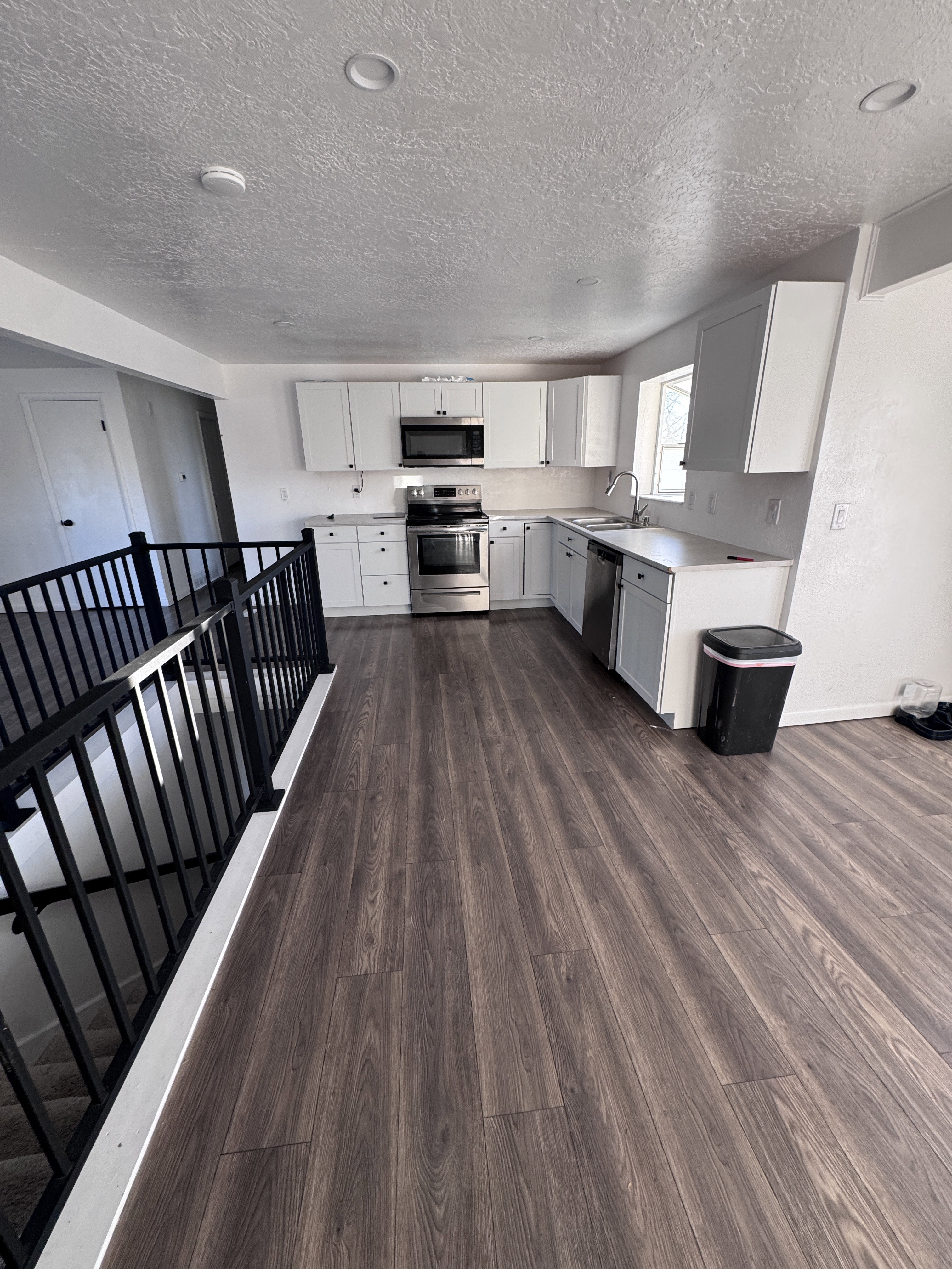 Kitchen with light countertops, appliances with stainless steel finishes, white cabinetry, dark wood finished floors, and a textured ceiling