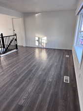 Unfurnished living room with dark wood-style flooring and a textured ceiling