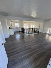 Unfurnished living room with dark wood-style flooring, a textured ceiling, and cooling unit