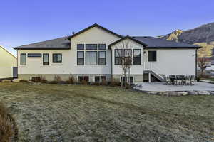 Rear view of house with a patio area, a yard, roof with shingles, and stucco siding
