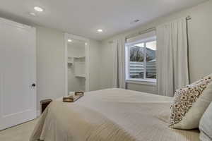 Bedroom with a walk in closet, light colored carpet, and recessed lighting