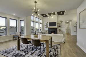 Dining room with a tile fireplace, healthy amount of natural light, light wood finished floors, beamed ceiling, and recessed lighting