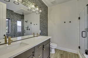 Full bathroom featuring double vanity, light wood-type flooring, and a shower stall
