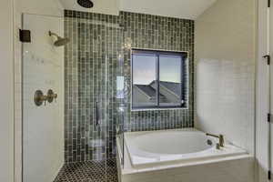 Bathroom with a garden tub, a shower stall, and tile walls