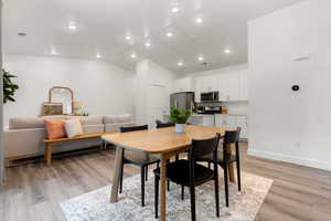 Dining room with lofted ceiling, light wood-type flooring, and recessed lighting