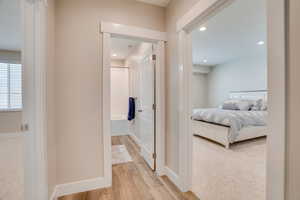 Hallway featuring light wood finished floors, light colored carpet, and recessed lighting