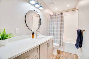 Bathroom featuring vanity, shower / bathtub combination with curtain, light wood-style floors, and recessed lighting