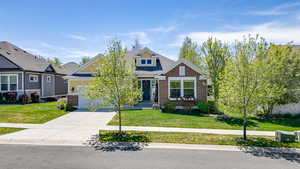 Craftsman-style house with driveway, brick siding, a front lawn, roof with shingles, and a garage