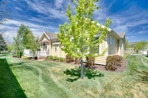 View of property exterior with a yard, a shingled roof, and a wooden deck