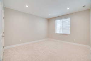 Empty room with light carpet and recessed lighting