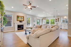 Living room featuring a glass covered fireplace, light wood-type flooring, recessed lighting, and ceiling fan