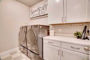 Washroom with tile patterned floors, independent washer and dryer, and cabinet space