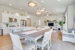 Dining room featuring vaulted ceiling, light wood finished floors, and a ceiling fan