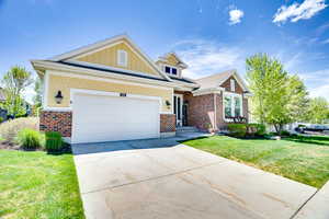 Craftsman house featuring a front lawn, driveway, a garage, board and batten siding, and brick siding