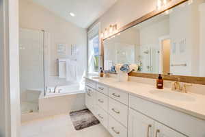 Bathroom with double vanity, a shower stall, lofted ceiling, a garden tub, and light tile patterned floors