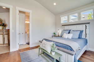 Bedroom with vaulted ceiling, recessed lighting, wood finished floors, and ensuite bathroom