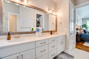 Bathroom with double vanity, ensuite bath, light tile patterned floors, and a walk in closet