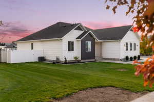 Back of house at dusk featuring a shingled roof