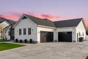 View of front facade with board and batten siding, concrete driveway, a garage, and roof with shingles