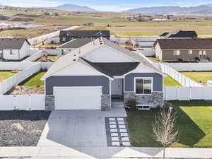 View of front of home with stone siding, driveway, a shingled roof, and a mountain view