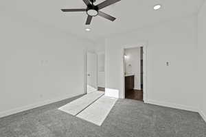 Primary bedroom with dark carpet, ensuite bath, ceiling fan, and recessed lighting