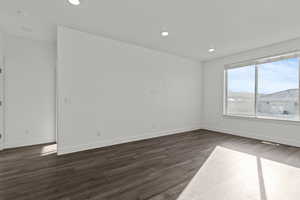 Empty room with dark wood-type flooring and recessed lighting