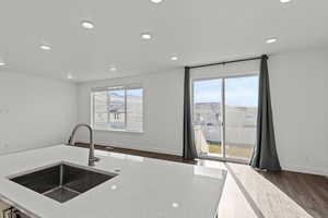 Kitchen featuring light stone counters, recessed lighting, dark wood-style flooring, and open floor plan