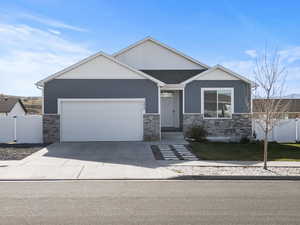 View of front facade with stone siding, driveway, an attached garage, and board and batten siding