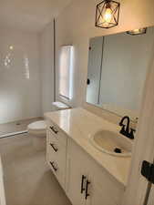 Bathroom featuring vanity, tiled shower, and lofted ceiling