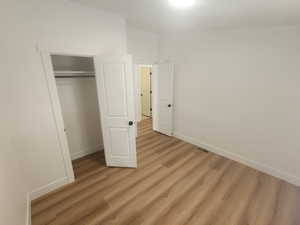 Unfurnished bedroom with light wood-style floors and a closet