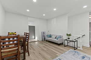 Living area with an upstairs landing, recessed lighting, and light wood-type flooring