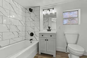 Master bathroom with vanity, shower / washtub combination, light wood finished floors, and a textured ceiling