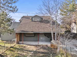 Rear view of property with roof with shingles and a patio