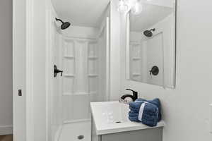 Full bath featuring a shower stall, vanity, a textured wall, and a textured ceiling