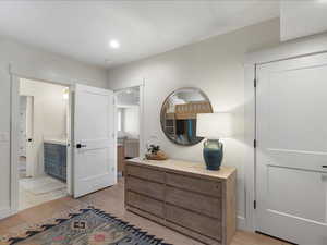 Bedroom with light wood finished floors, ensuite bathroom, and recessed lighting