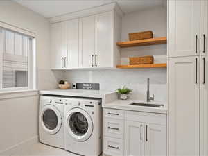 Laundry area featuring washing machine and dryer, cabinet space, and light tile patterned flooring